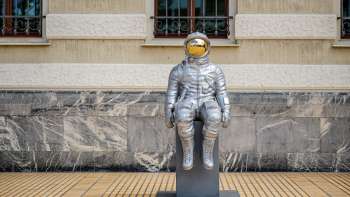 Silver astronaut sculpture "Raumableiter" by Max Grüter in front of the government building in Vaduz - modern art in public space.