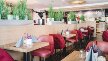 : Generously laid tables in the PUR Restaurant & Bar with red chairs and floral table decorations.