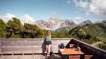 A woman enjoys the view of the Liechtenstein Alps and the Rhine Valley from the Sareis viewing terrace on a clear day