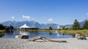 Natural bathing area with sand, driftwood, and views of the surrounding mountains