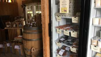 Regional range in the Hedihof farm store - fridge with packaged meat products and rustic sales room.