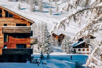 Cozy chalets in the winter sports resort of Malbun surrounded by snow-covered trees and ski slopes in the background
