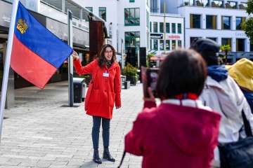 City guide presents the Liechtenstein flag during a guided tour through the center of Vaduz
