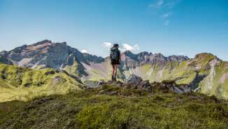 Hiker on a summit in Liechtenstein with a view of an impressive mountain range - summer, freedom and pure nature