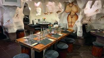 Close-up of a cozy restaurant with wooden tables and chairs, decorated with flowers and candles