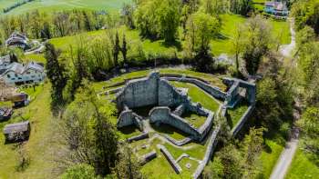 Aerial view of the castle ruins of Schellenberg, surrounded by dense forest and meadows