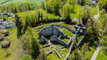 Aerial view of the castle ruins of Schellenberg, surrounded by dense forest and meadows