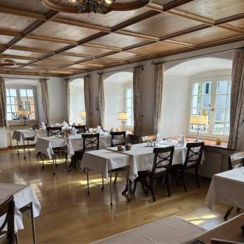 Bright, classic dining room with white tablecloths and wooden floor.