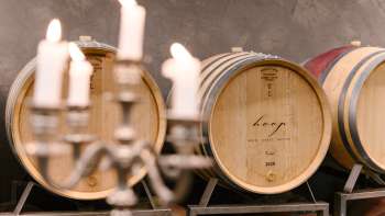 Atmospheric shot in the wine cellar of the Hoop winery with labeled barrique barrels and candlelight.
