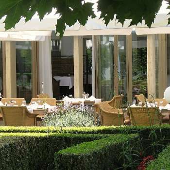 Sunny garden terrace of the Vivid restaurant with set tables and a view of the greenery