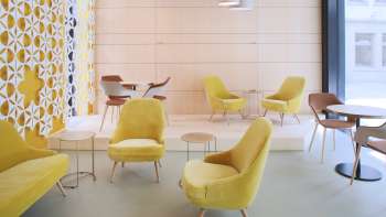 Modern café with stylish yellow armchairs, minimalist furnishings and bright windows