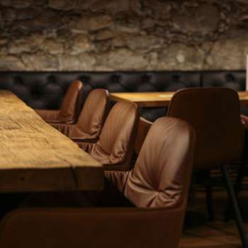 Close-up of a wooden table with comfortable leather chairs in the cozy seating area of the WY Weinbar.