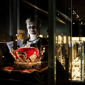 Woman looking at the princely hat in the Liechtenstein TreasureChamber, surrounded by illuminated display cases.