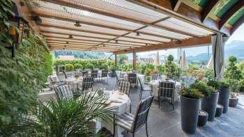 Elegant restaurant terrace with covered tables and panoramic views of the Liechtenstein Alps.