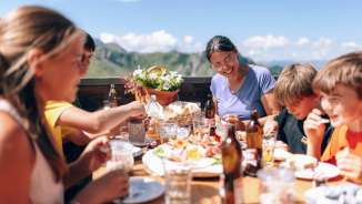 Family having lunch together on a sunny terrace in Sarreis, surrounded by mountains and regional specialties