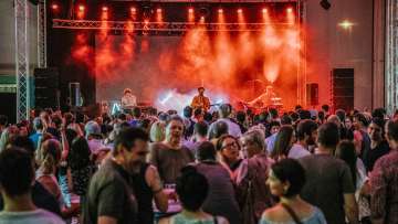 Concert by the band Baba Shrimps at the FL1.LIFE Festival with red stage lighting and a large audience
