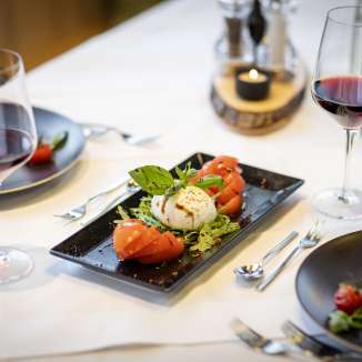 Fresh tomato and mozzarella salad with red wine on a laid table at the JUFA Hotel Malbun