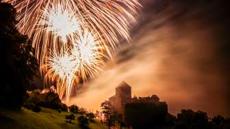 Vaduz Castle in Liechtenstein at night with large fireworks in the sky - atmospheric shot with light and fog