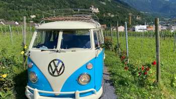 Nostalgic VW bus on a path through the vineyards with a view of Vaduz Castle