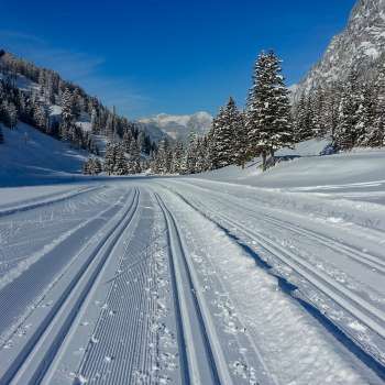 Freshly groomed cross-country ski trail in Steg with panoramic views of the snow-covered Alpine landscape