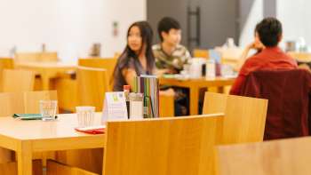 Guests sit at wooden tables in the café in the Liechtenstein Art Museum, chatting and enjoying the atmosphere.