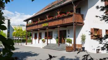 Exterior view of the Vivid restaurant with traditional façade, wooden balcony and flower boxes in bloom