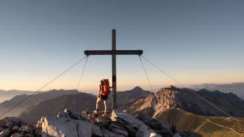 Hiker at the summit cross on Augstenberg mountain
