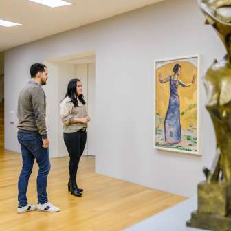 Couple looking at paintings in the bright gallery of the Kunstmuseum Liechtenstein with modern sculpture in the foreground.