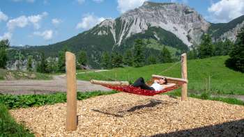 A woman lies relaxed on a hammock along the swinging path
