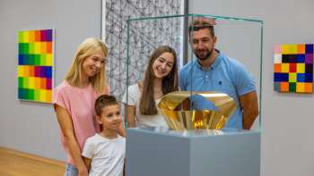 A family looks at a glass display case containing a golden sculpture at the Liechtenstein Art Museum