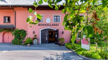 Entrance area of the Court Winery of the Prince of Liechtenstein in Vaduz, surrounded by green foliage and flowers.