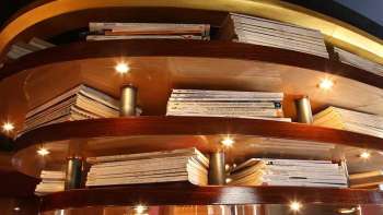 Wooden shelf with illuminated books as ceiling cladding