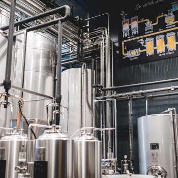 View of the brewery's technical room with its complex piping system and modern stainless steel tanks.
