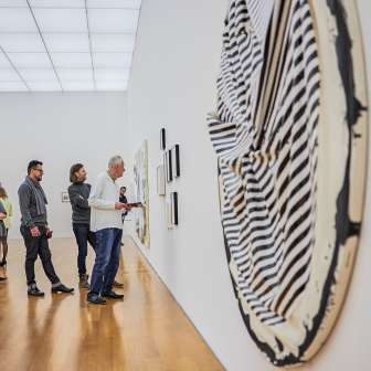 Visitors view modern works of art in a gallery of the Liechtenstein Art Museum with bright architecture and wooden flooring