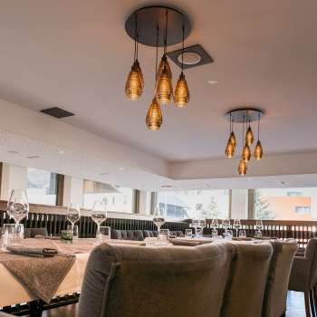 Modern restaurant area with a view of the window front and stylish hanging lamps.