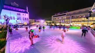 People ice skating on the illuminated ice rink of Vaduz on Ice in the city center of Vaduz in the evening