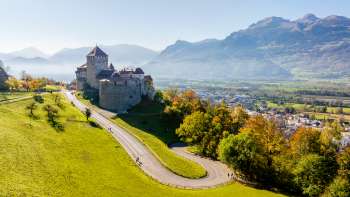 Vaduz Castle on a hill overlooking the Rhine Valley and surrounding mountains.