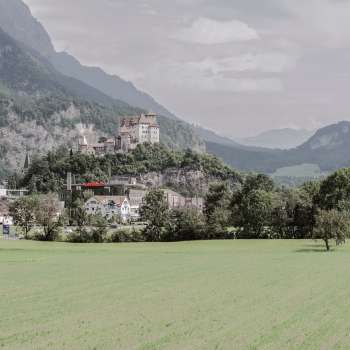 Majestic view of Gutenberg Castle in Balzers, surrounded by green fields and the impressive Alps.