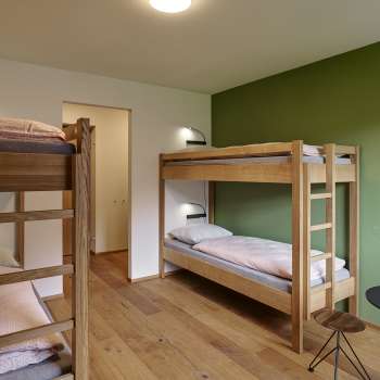 Four-bed room with bunk beds and wooden floor at Schaan/Vaduz Youth Hostel