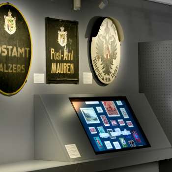 Museum room with old post signs and a digital display on the history of the post office in Liechtenstein.