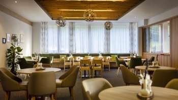 Another corner of the dining area, with the same round tables, a cozy atmosphere and modern lighting installations.