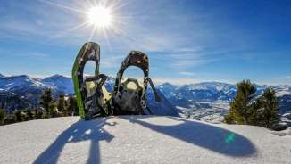 Two snowshoes in snow-covered Malbun with a panoramic view of the Alps on the Alpspitz in Liechtenstein in bright sunshine