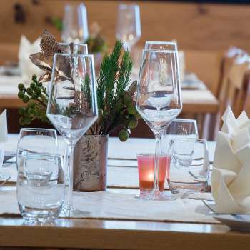 Close-up of a beautifully laid table with glasses, cutlery and a small plant decoration.