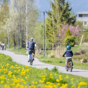 Family cycling on the spring cycle path in the Haberfeld Nature Park, surrounded by flowering meadows and trees.