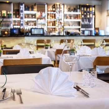  Tastefully laid table in the Alpspitz restaurant with a view of the bar in the background.