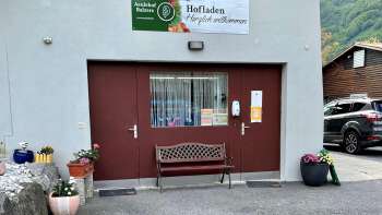Entrance to the Aeulehof farm store with red gate, bench and floral decorations in Triesen, Liechtenstein.