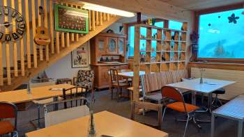 Guest room with window front and decoration - tables and chairs in an open room with large windows and a view of the green outdoor area.