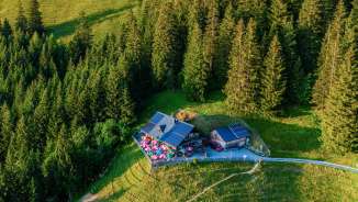 Aerial view of the Gafadura hut on a sunny mountain slope, surrounded by forests and alpine meadows in Liechtenstein