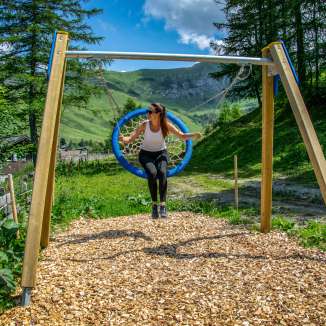 Woman swinging on a nest swing in Malbun, Liechtenstein, surrounded by mountains, meadows and summer nature