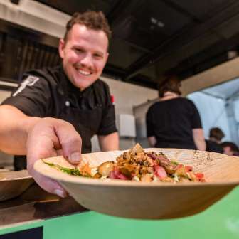 Chef serves a plate of regional dishes at the Genussfestival Vaduz, Liechtenstein - culinary event with a focus on enjoyment